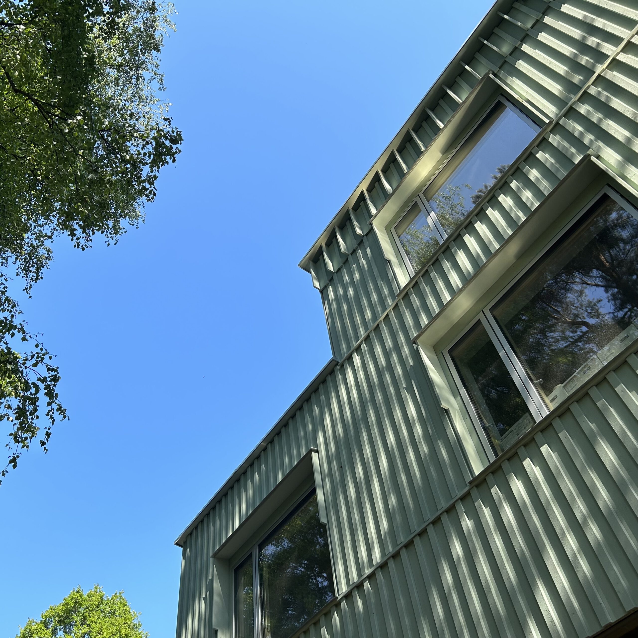 Holzfassade mit Fensterbändern, Blick von unten in den Himmel